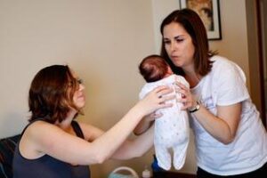 doula handing baby to mom in bed